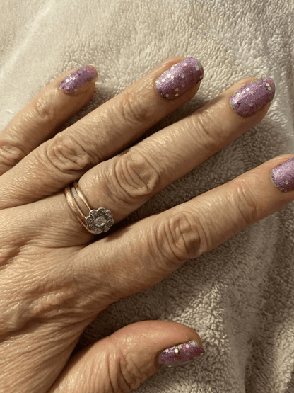 Mauve-pink nail wraps with chunky silver and purple glitter on short round nails