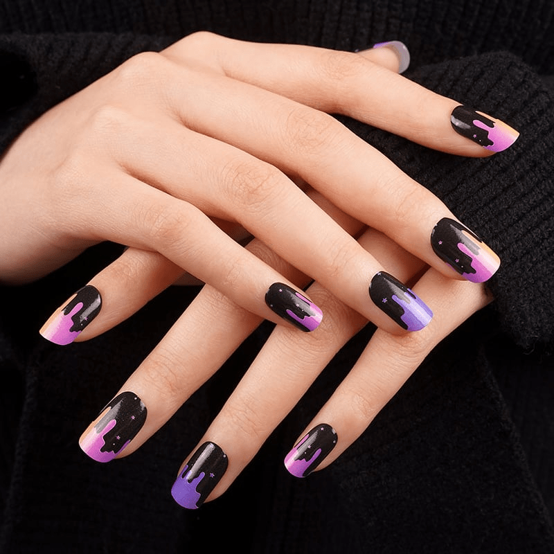 Hands wearing colourful ombré nail wraps with black drip design manicure art