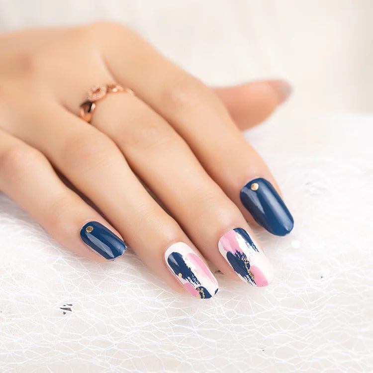 Navy blue nail wraps with pink and white abstract brushstroke accents, gold dot detail