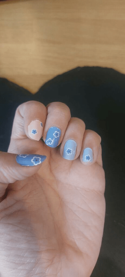 Blue and pink floral nail wraps applied on hand showing daisy pattern design