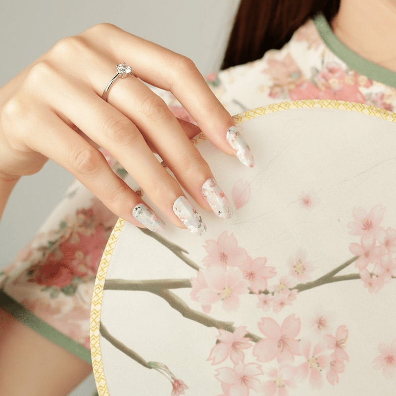 Pink cherry blossom nail wraps on hand holding teacup at-home manicure