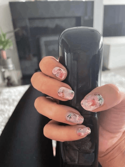 Hand holding phone showing pink floral nail wraps with cherry blossom pattern