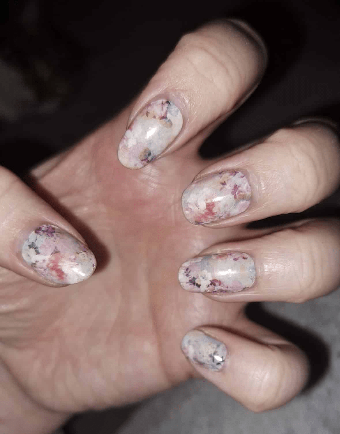 Hand wearing pink watercolor floral nail wraps with delicate blossom pattern design