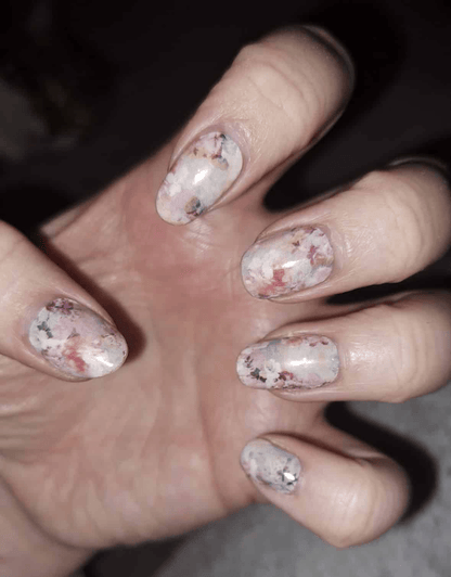 Hand wearing pink watercolor floral nail wraps with delicate blossom pattern design