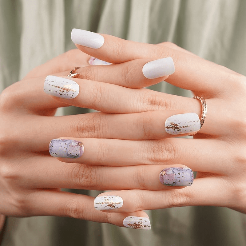White and purple floral nail wraps on hands showing watercolour blossom manicure