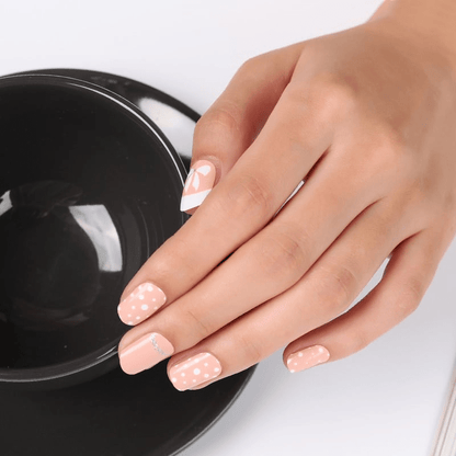 Peach nail wraps with white polka dots, a bow accent and silver glitter stripe
