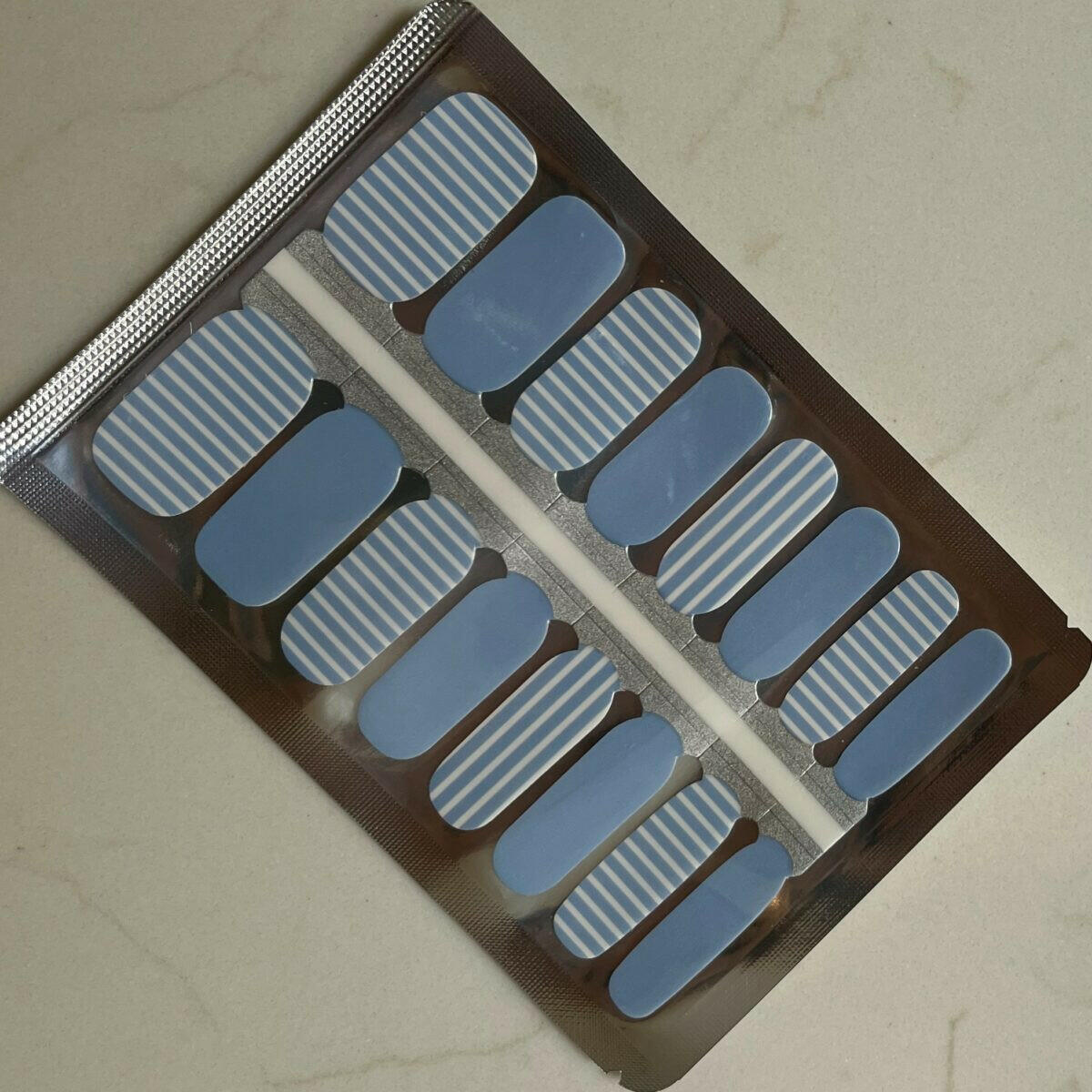 Blue and white striped nail wraps in packaging showing Breton pattern design