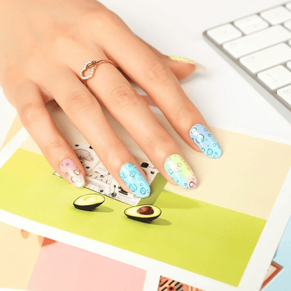 Hand with rainbow bubble nail wraps over keyboard displaying trendy nail art