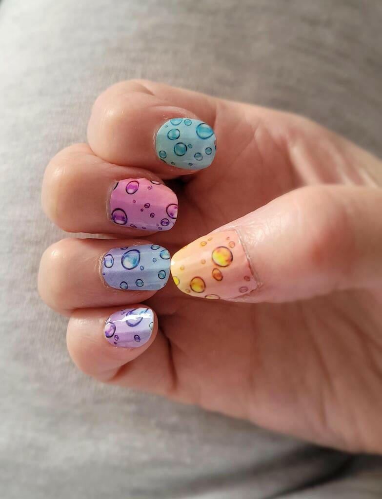 Colourful bubble nail art on hand showcasing pastel nail wraps design
