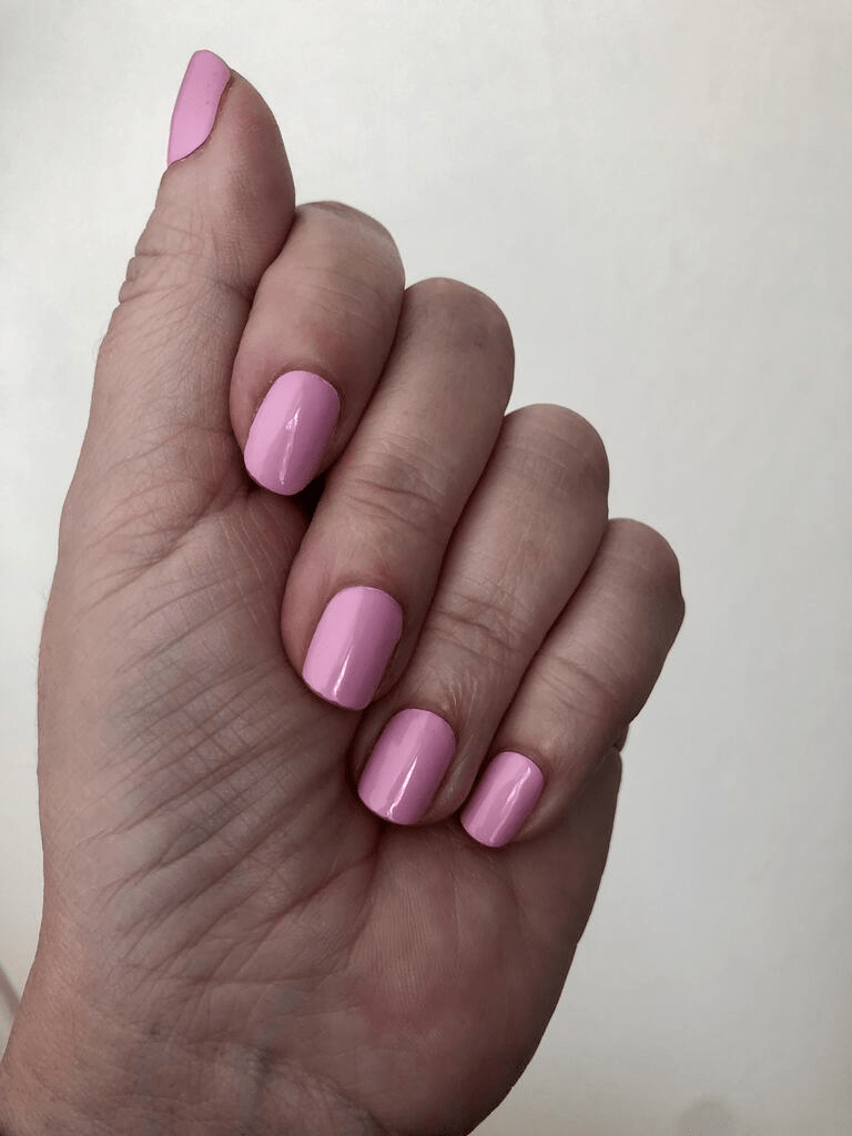 Hand wearing glossy bubblegum pink nail wraps in classic solid colour finish