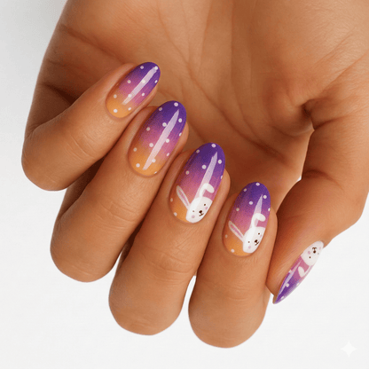 Purple orange gradient nail wraps on hand featuring cute white bunny rabbit Easter designs