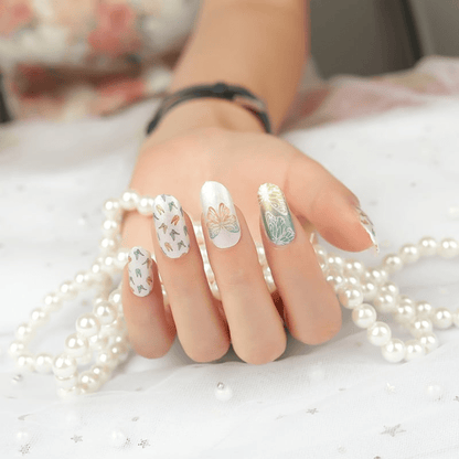 Elegant hand with butterfly nail art wraps in white and gold on white pearls