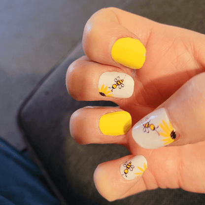 Yellow and white nail wraps with cute bee design on hand nail art