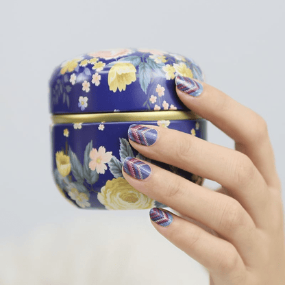 Purple blue chevron cable knit nail wraps on hand beside floral ceramic jar