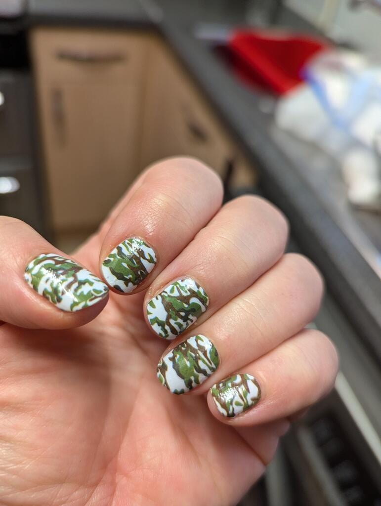 Green camouflage nail wraps applied on hand showing military pattern nail art design