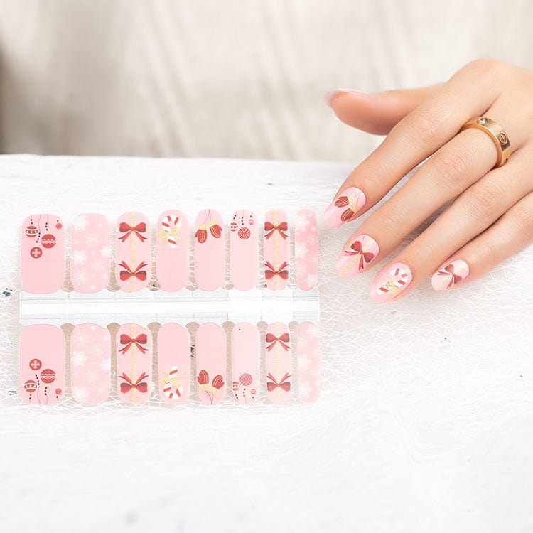 Christmas nail wraps sheet with pink candy cane and bow designs shown with hand