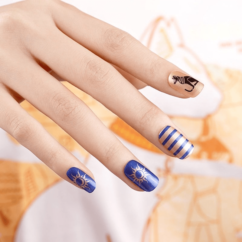 Nail wraps in gold and blue with cat motif, stripes, and sun-moon Egyptian design