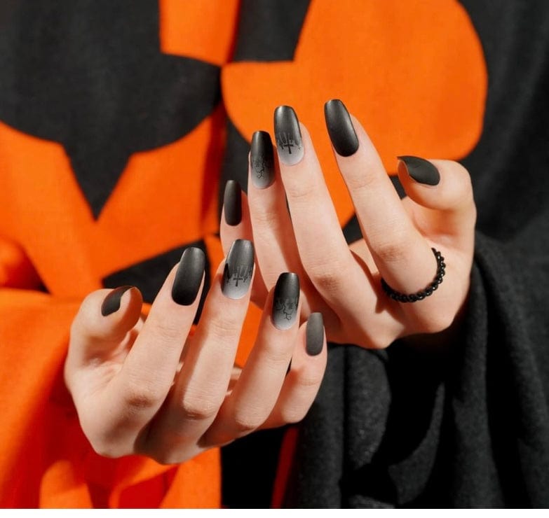 Black and grey gothic cemetery nail wraps on hands against orange Halloween background