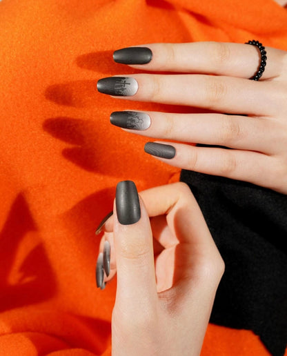 Hand wearing dark grey gothic cemetery nail wraps with graveyard pattern design
