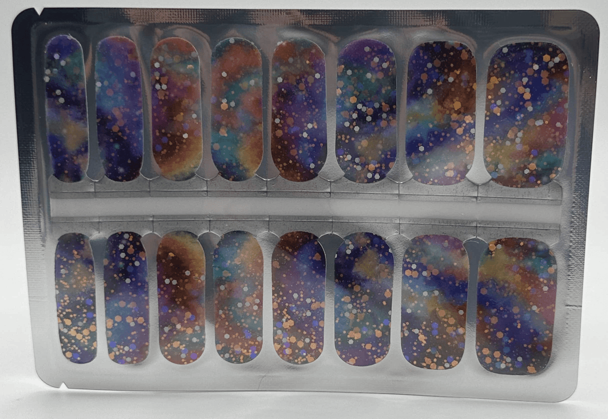 Cosmic glitter nail wraps in packaging featuring purple blue gold sparkle nail art
