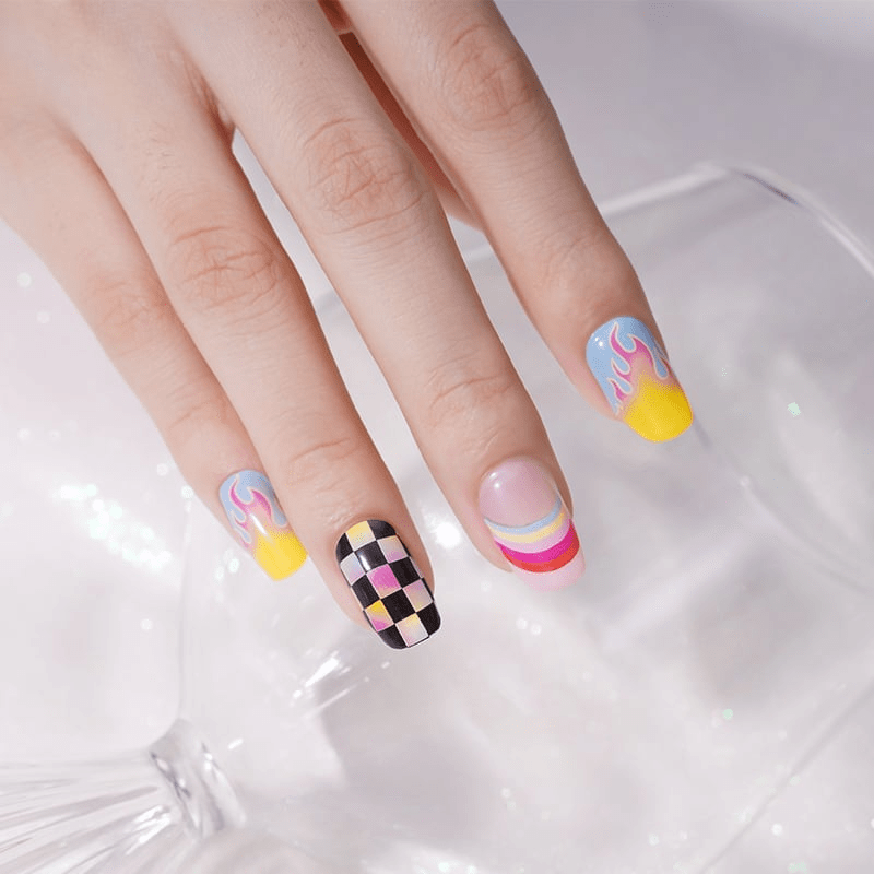 Hand wearing vibrant 80s nail wraps with chequered patterns and rainbow swirls