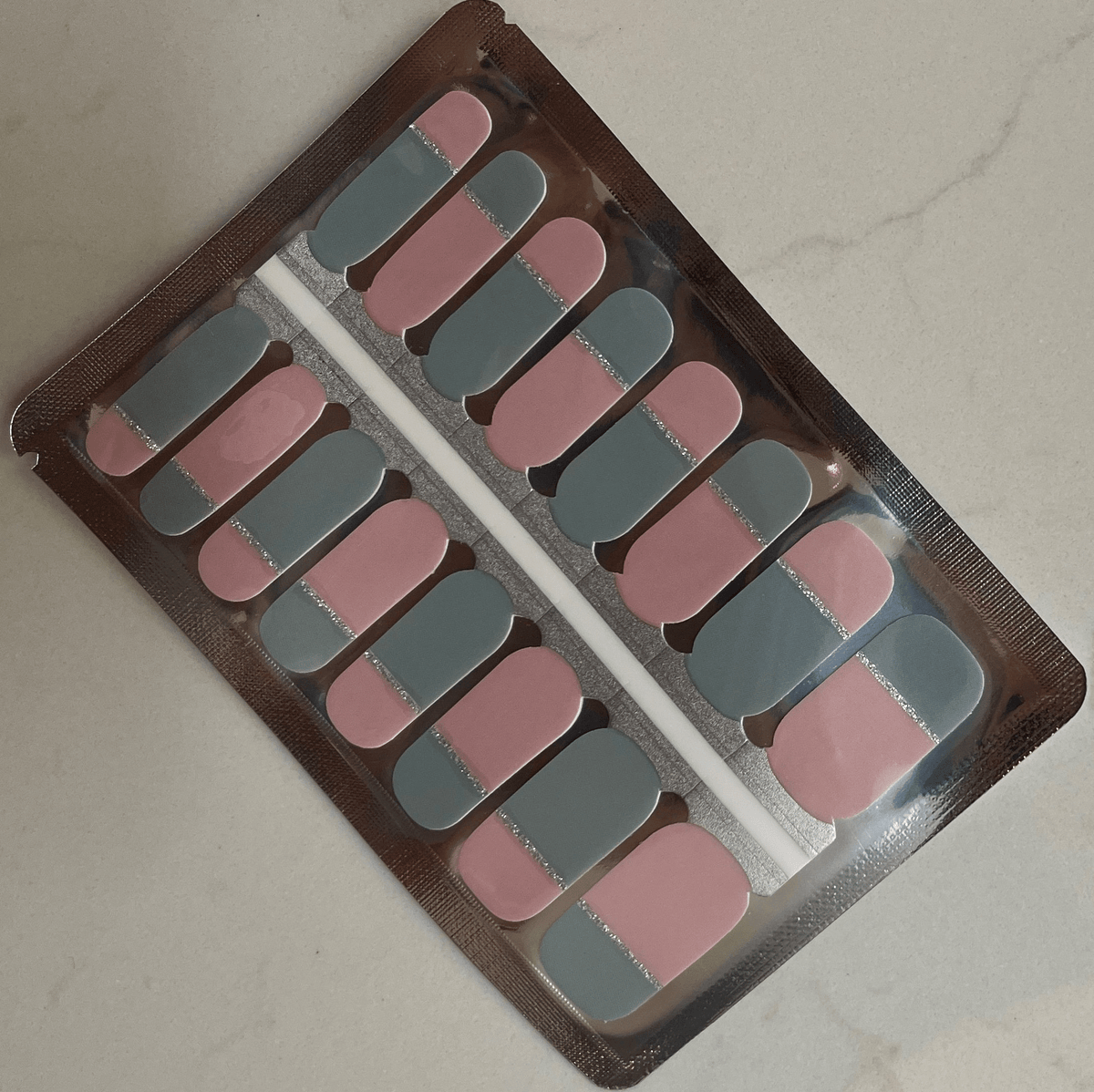 Nail wraps in dusty pink and grey, split design with a silver glitter centre line