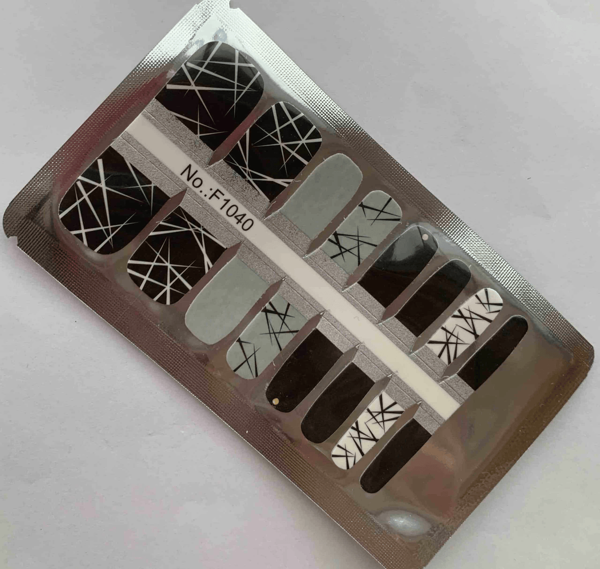 Non-UV pedicure nail wraps in packaging featuring black geometric criss-cross patterns on clear backing