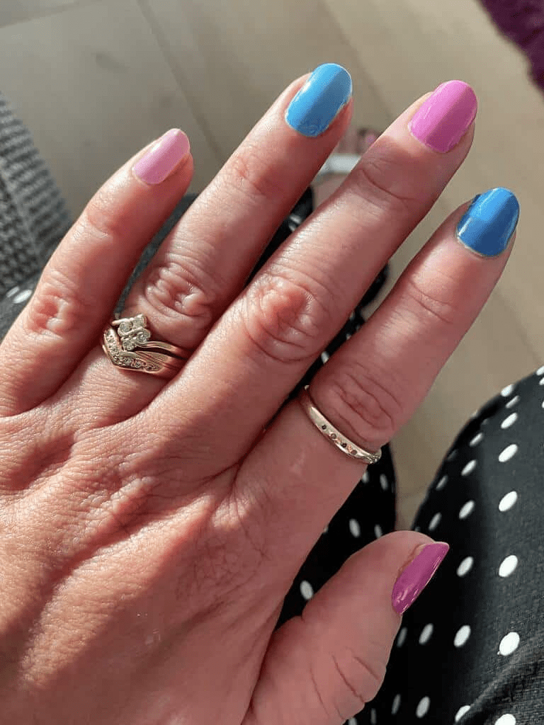 Hand wearing alternating blue and pink glossy nail wraps classic manicure style