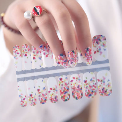 Hand holding multicoloured confetti pattern nail wraps with pink blue white dots
