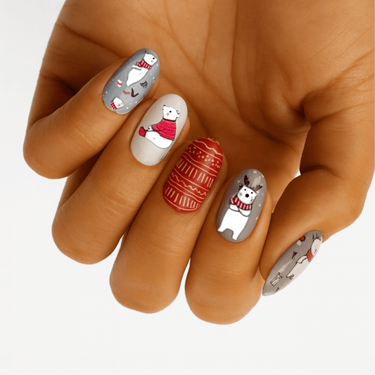 Christmas polar bear nail wraps on hand with red festive designs and white base