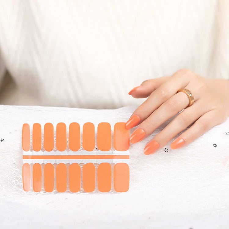 Coral orange nail wraps sheet with hand showing glossy manicure results