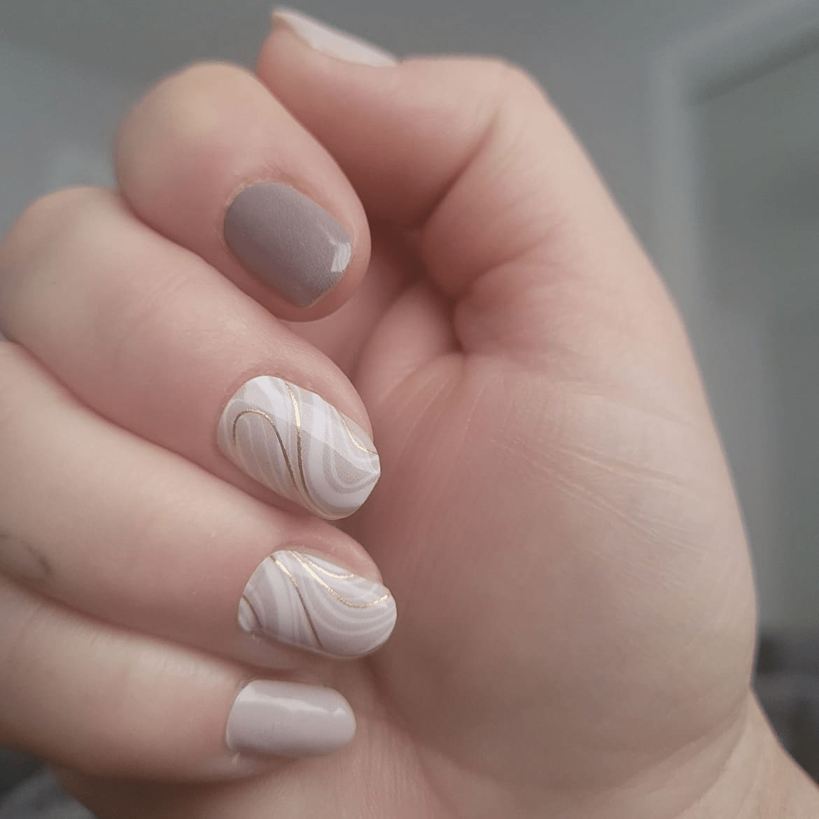 Neutral marble nail wraps on hand showing cream and taupe nail art