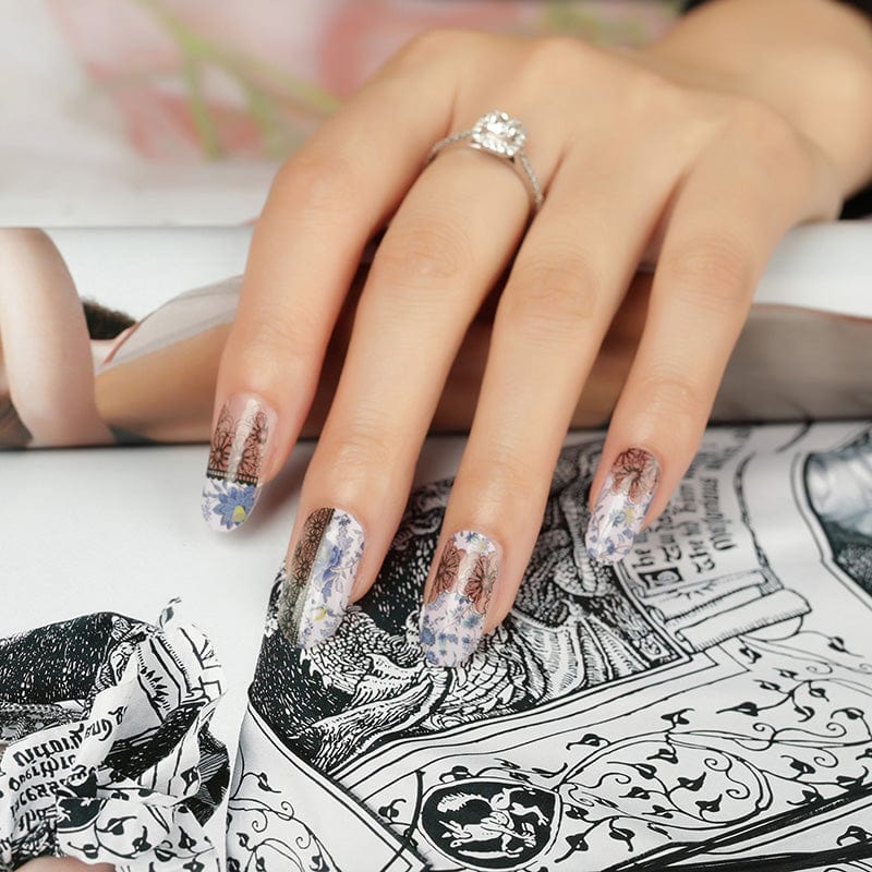 Hand wearing purple floral nail wraps with black crochet lace nail art design