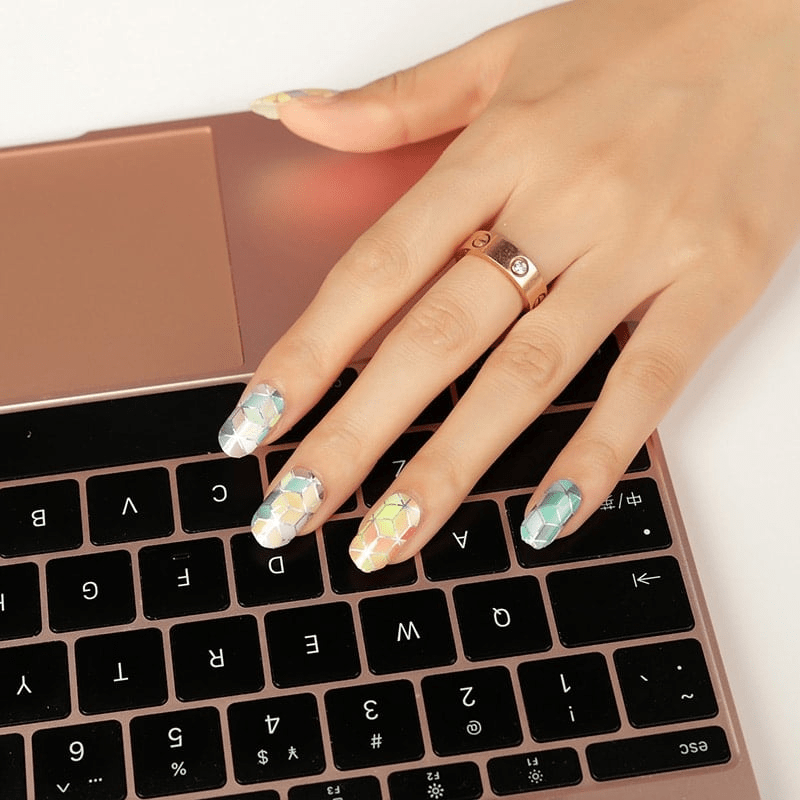Hand on laptop showing geometric cube nail wraps multicoloured at-home manicure design