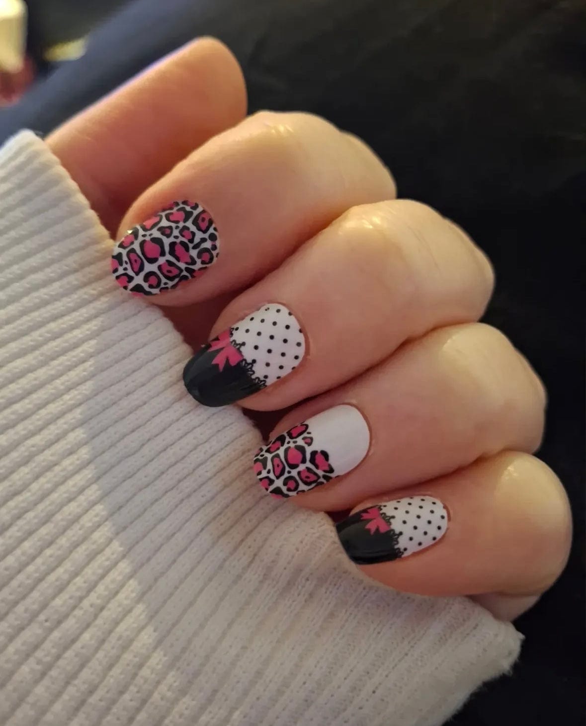 Hand displaying mixed pattern nail art with leopard print, black and white polka dots