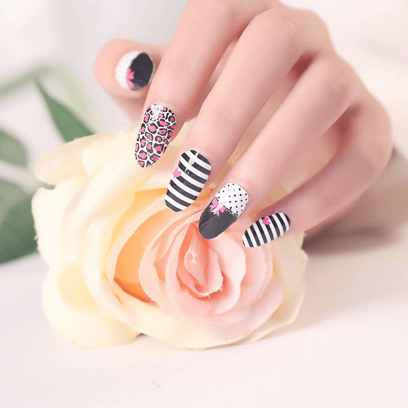 Hand wearing mixed pattern nail wraps with black polish, leopard print, stripes and polka dots