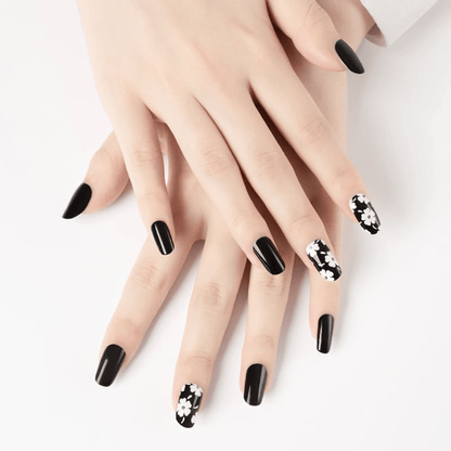 Glossy black nail wraps with white daisy floral accent on select nails