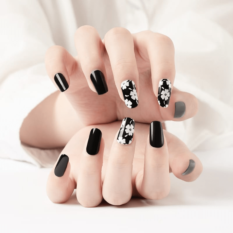 Black and white daisy nail wraps on hands showing gothic floral nail art design