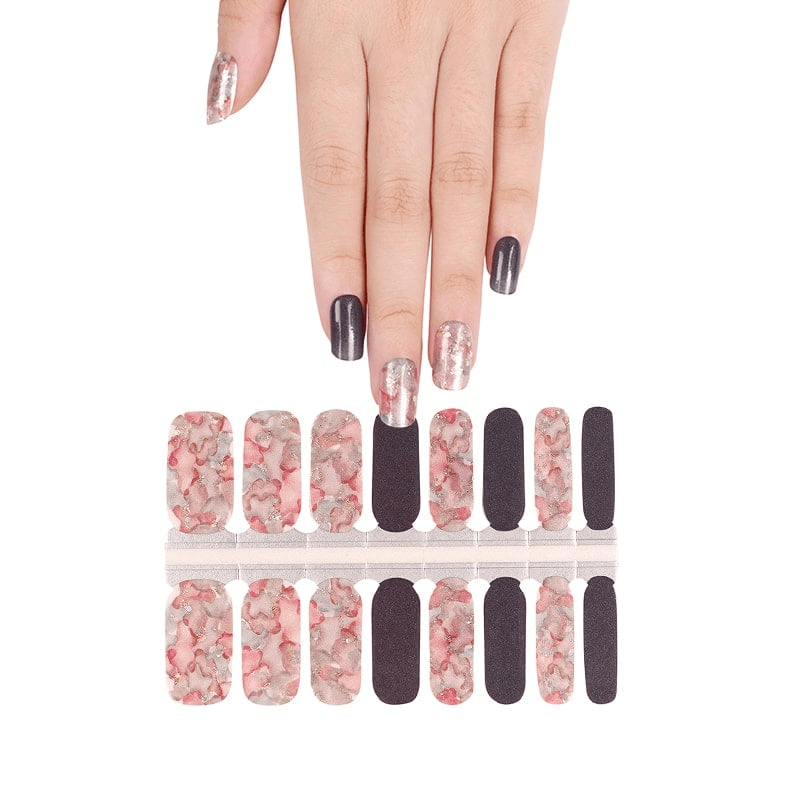Hand displaying coral watercolour nail wraps with black accent nails for at-home manicure
