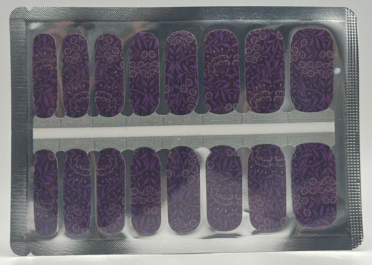 Sheet of purple botanical nail wraps featuring dark leaf patterns and white flowers