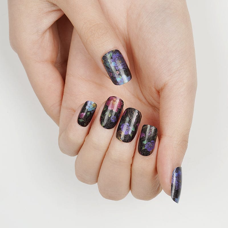 Black floral nail wraps with vibrant purple blue pink flowers, hand displaying manicure