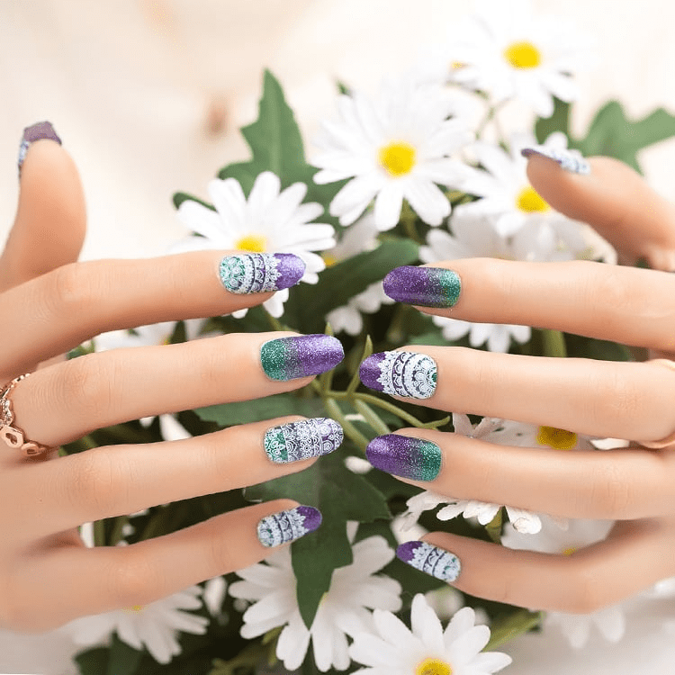 Sparkly purple and turquoise gradient nail wraps on hands with white daisy flowers background