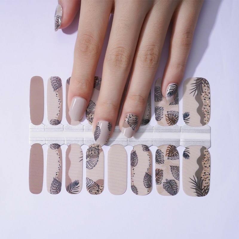 Brown palm leaf nail wraps on hand showing tropical feather pattern design