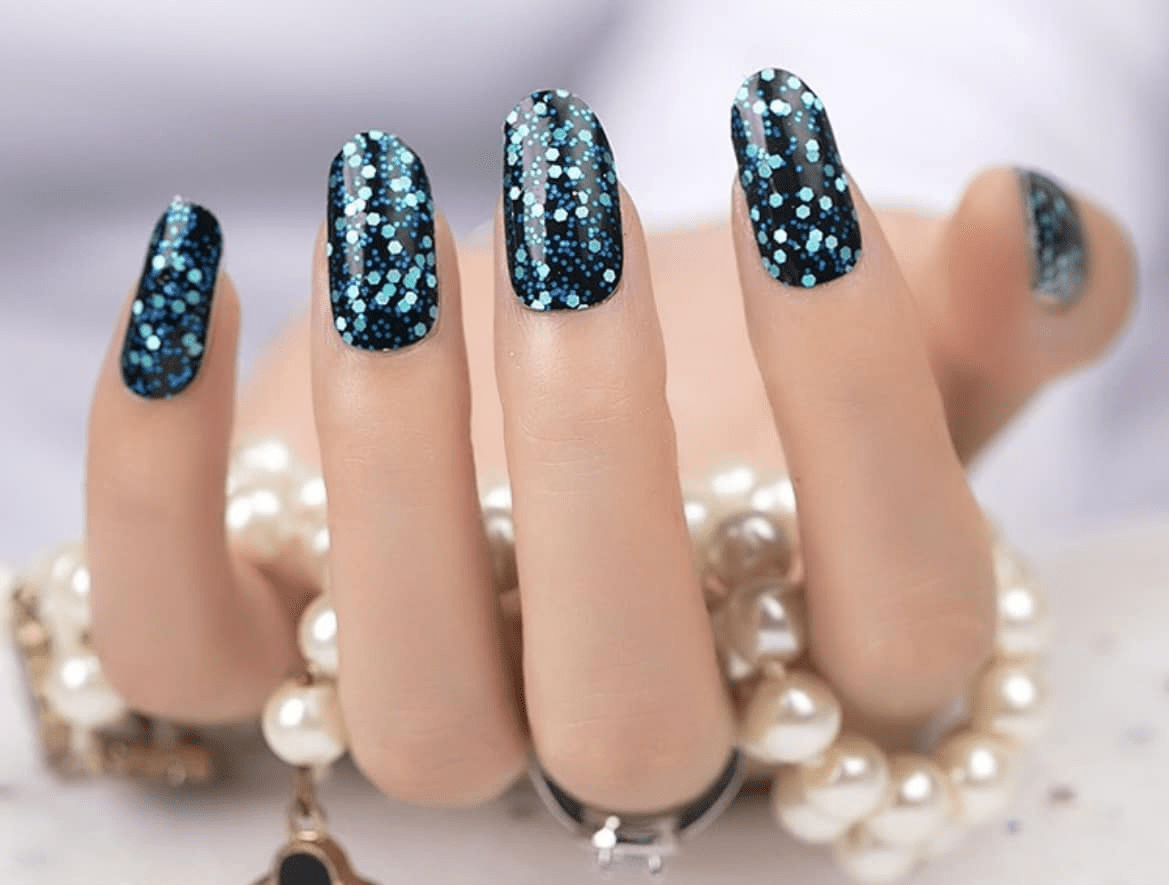 Hand wearing dark teal glitter nail wraps with holographic sequins for party manicure