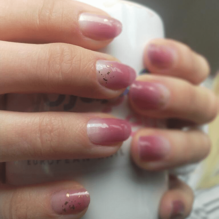 Mauve-pink glossy nail wraps with subtle gold foil fleck accents on short round nails