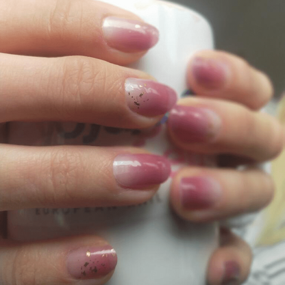 Mauve-pink glossy nail wraps with subtle gold foil fleck accents on short round nails