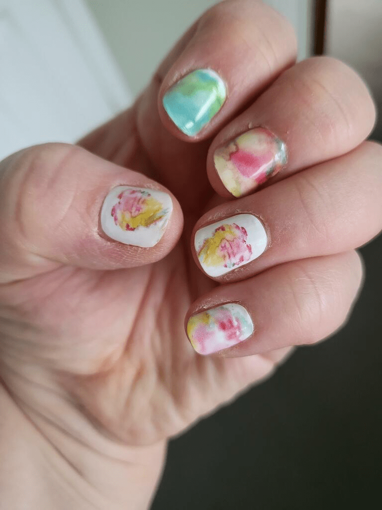 Hand showing watercolour nail wraps with soft pastel pink green abstract artistic design