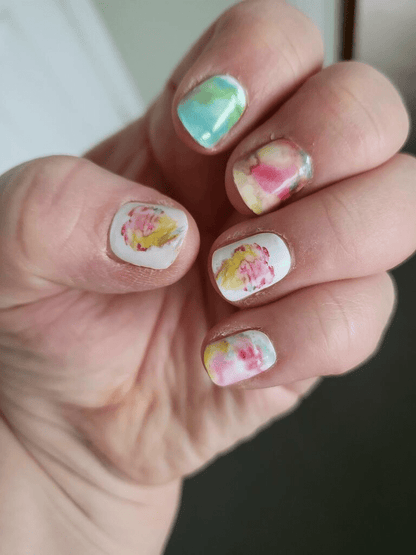 Hand showing watercolour nail wraps with soft pastel pink green abstract artistic design