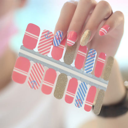 Hand wearing coral pink blue striped nautical nail wraps with gold glitter accent nails