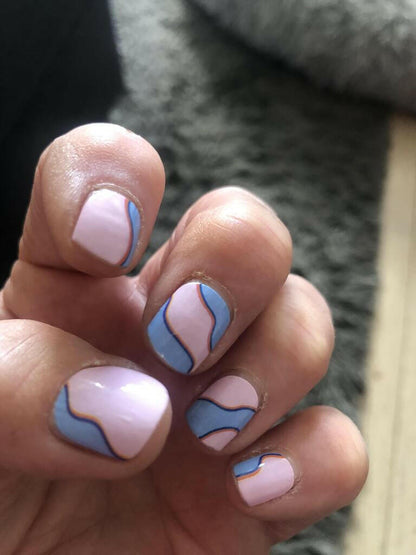 Hand wearing abstract blue pink wave nail wraps with modern artistic pattern